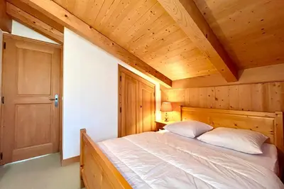 a bed in a room with a wooden ceiling at Éclat Alpin in Combloux