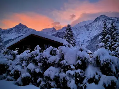 a house covered in snow with mountains in the background at Logan - Appartement spacieux 4 chambres - Animaux acceptés - Parking - FR-1-343-266 in Les Houches