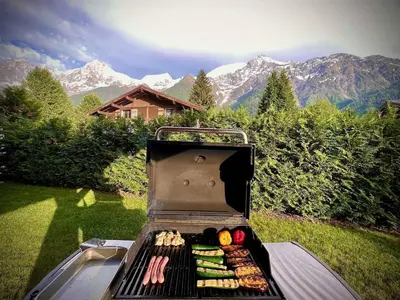 a grill with food on it with mountains in the background at Logan - Appartement spacieux 4 chambres - Animaux acceptés - Parking - FR-1-343-266 in Les Houches