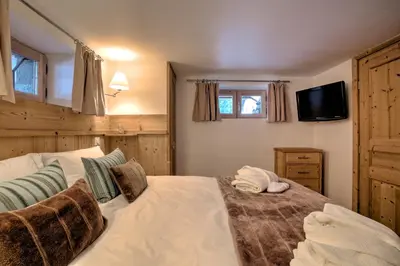 a bedroom with a large white bed with a television at Chalet Cristalliers - 5 Bedroom luxury chalet in central Chamonix with log fire and hot tub in Chamonix-Mont-Blanc