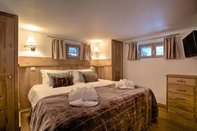 a bedroom with a large bed with two towels on it at Chalet Cristalliers - 5 Bedroom luxury chalet in central Chamonix with log fire and hot tub in Chamonix-Mont-Blanc