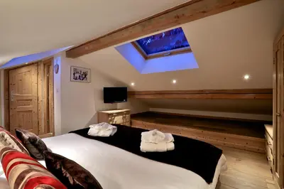a bedroom with a large bed and a skylight at Chalet Cristalliers - 5 Bedroom luxury chalet in central Chamonix with log fire and hot tub in Chamonix-Mont-Blanc