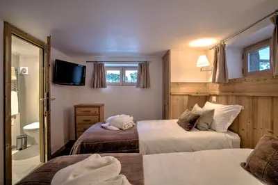 a bedroom with two beds and a tv on the wall at Chalet Cristalliers - 5 Bedroom luxury chalet in central Chamonix with log fire and hot tub in Chamonix-Mont-Blanc