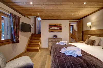 a bedroom with two beds and a tv and stairs at Chalet Cristalliers - 5 Bedroom luxury chalet in central Chamonix with log fire and hot tub in Chamonix-Mont-Blanc