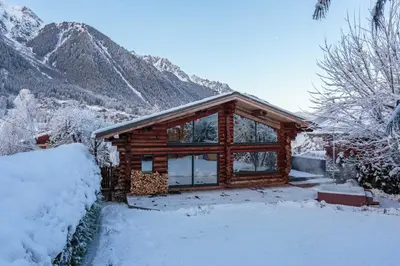 a log cabin in the snow with mountains in the background at Chalet des Cimes - Chamonix All Year in Chamonix-Mont-Blanc
