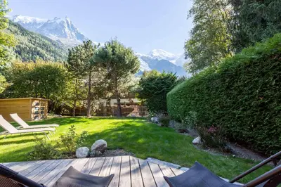 a backyard with a wooden deck with a view of mountains at Chalet des Cimes - Chamonix All Year in Chamonix-Mont-Blanc