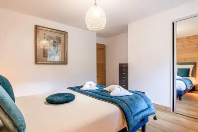 a bedroom with a bed with a blue blanket on it at Appartement moderne - Les houches in Les Houches