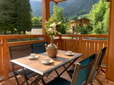 a table on a balcony with a vase of flowers at Appartement moderne - Les houches in Les Houches