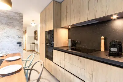a kitchen with wooden cabinets and a table and chairs at Appartement moderne - Les houches in Les Houches