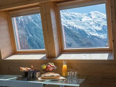 a table with a bowl of fruit in front of two windows at Penthouse Le Paradis I Le Chalet Club in Chamonix-Mont-Blanc