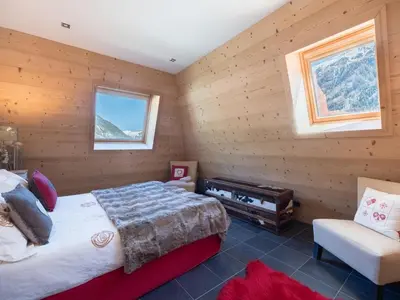 a bedroom with wooden walls and a bed and a chair at Penthouse Le Paradis I Le Chalet Club in Chamonix-Mont-Blanc