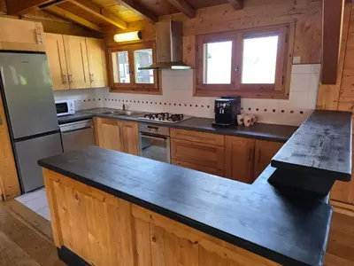 a kitchen with wooden cabinets and a black counter top at Grand appartement proche centre in Megève