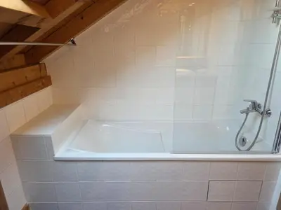a bath tub with a shower in a bathroom at Grand appartement proche centre in Megève