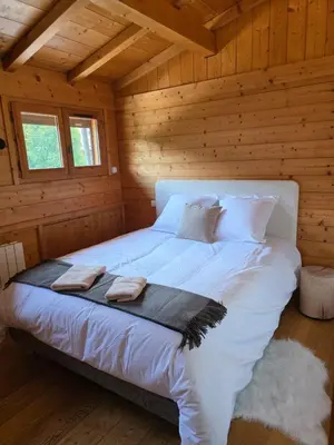 a bedroom with a white bed in a wooden cabin at Grand appartement proche centre in Megève