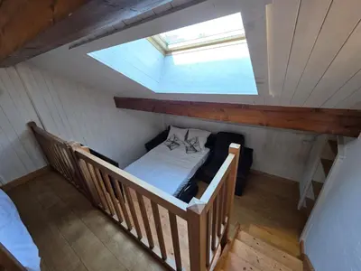 a room with a bed in a attic with a skylight at Grand appartement proche centre in Megève