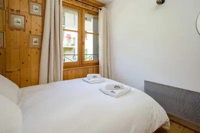 a bedroom with a white bed with a window at Val d'Arve Apartment - Chamonix All Year in Chamonix-Mont-Blanc