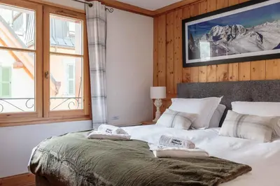 a bedroom with a large white bed with a window at Val d'Arve Apartment - Chamonix All Year in Chamonix-Mont-Blanc