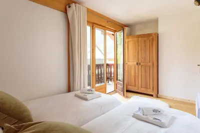 a bedroom with two beds and a large window at Val d'Arve Apartment - Chamonix All Year in Chamonix-Mont-Blanc