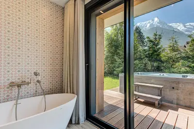 a bathroom with a tub and a large window at Chalet Papillon - Alpes Travel - Detached Chalet - Les Praz - Sleeps 8-10 in Chamonix-Mont-Blanc