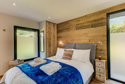 a bedroom with a bed with a wooden wall at Chalet Papillon - Alpes Travel - Detached Chalet - Les Praz - Sleeps 8-10 in Chamonix-Mont-Blanc