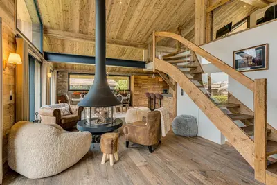 a living room with a wooden ceiling and a spiral staircase at Chalet Papillon - Alpes Travel - Detached Chalet - Les Praz - Sleeps 8-10 in Chamonix-Mont-Blanc