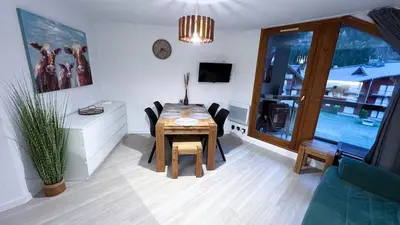 a dining room with a table and chairs and a tv at 3 cows in Les Contamines-Montjoie