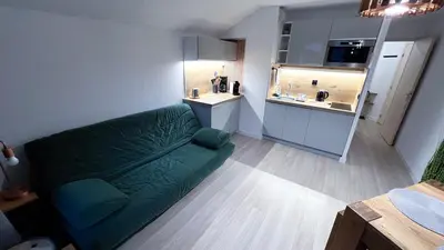 a living room with a green couch and a kitchen at 3 cows in Les Contamines-Montjoie