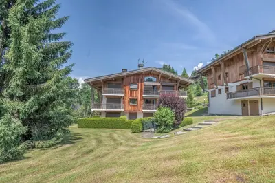 a large house with a yard in front of it at Appartement Le clos de Rochebrune - Welkeys in Megève