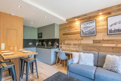 a living room with a blue couch and a kitchen at Appartement Le clos de Rochebrune - Welkeys in Megève