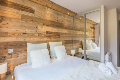 a bedroom with a wooden wall with two beds at Appartement Le clos de Rochebrune - Welkeys in Megève