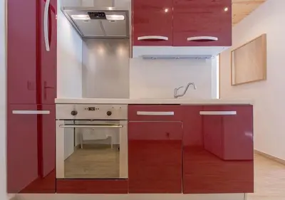 a kitchen with red cabinets and a stainless steel stove at Résidence Le Relax - Megève Centre in Megève