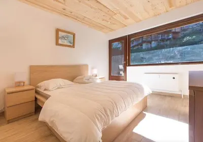 a bedroom with a large bed and a large window at Résidence Le Relax - Megève Centre in Megève