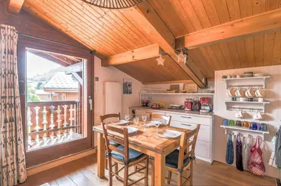 a kitchen with a wooden table and a large window at Appartement Warens - Welkeys in Megève