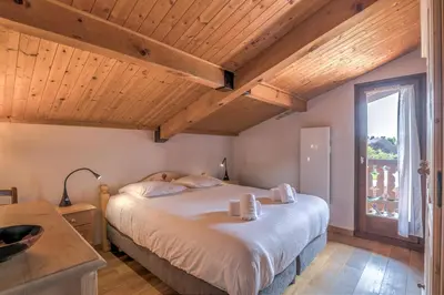 a bedroom with a large bed and a window at Appartement Warens - Welkeys in Megève