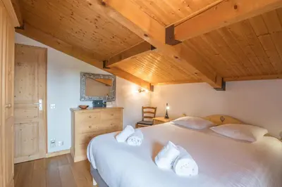 a bedroom with a large white bed and wooden ceilings at Appartement Warens - Welkeys in Megève