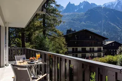 a table and chairs on a balcony with a view of mountains at Le Brevent apartment -Chamonix All Year in Chamonix-Mont-Blanc