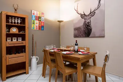 a dining room table with chairs and a deer painting on the wall at Le Majestic 76 - Chamonix All Year in Chamonix-Mont-Blanc