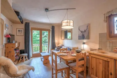 a kitchen and living room with a table and chairs at Studio Montée du Calvaire - Welkeys in Megève