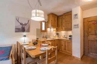 a kitchen with a wooden table and a dining room at Studio Montée du Calvaire - Welkeys in Megève