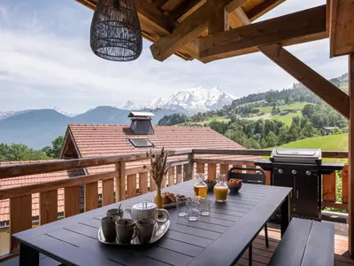 a table on a balcony with a view of mountains at Chalet Double M I Le Chalet Club in Combloux