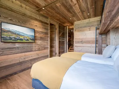 two beds in a room with wooden walls at Chalet Double M I Le Chalet Club in Combloux