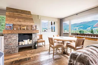 a living room with a fireplace and a table and chairs at Apartment with balcony 10 min walk from the slopes in Megève