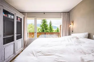 a bedroom with a large white bed and a window at Apartment with balcony 10 min walk from the slopes in Megève