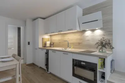 a kitchen with white cabinets and a sink at Studio Kayla - Espace bien-etre Piscine Face au Kandahar in Les Houches