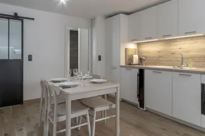 a kitchen with white cabinets and a table with chairs at Studio Kayla - Espace bien-etre Piscine Face au Kandahar in Les Houches