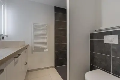 a bathroom with a sink and a shower with black tiles at Studio Kayla - Espace bien-etre Piscine Face au Kandahar in Les Houches