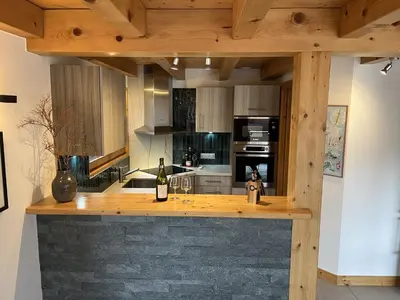 a kitchen with a wooden counter with a bottle of wine at Chalet Alpéa - Jacuzzi vue montagne - Neuf in Saint-Gervais-les-Bains