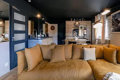 a brown couch in a living room with a kitchen at Au Bord de leau Ski & ete en famille in Megève