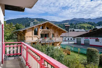 a wooden house with a red railing on a balcony at Au Bord de leau Ski & ete en famille in Megève