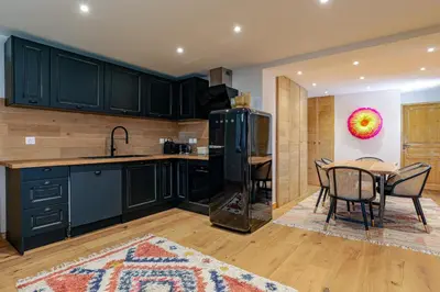 a kitchen with black cabinets and a table and chairs at Cocoon - Jardin privé au cœur de Megève in Megève